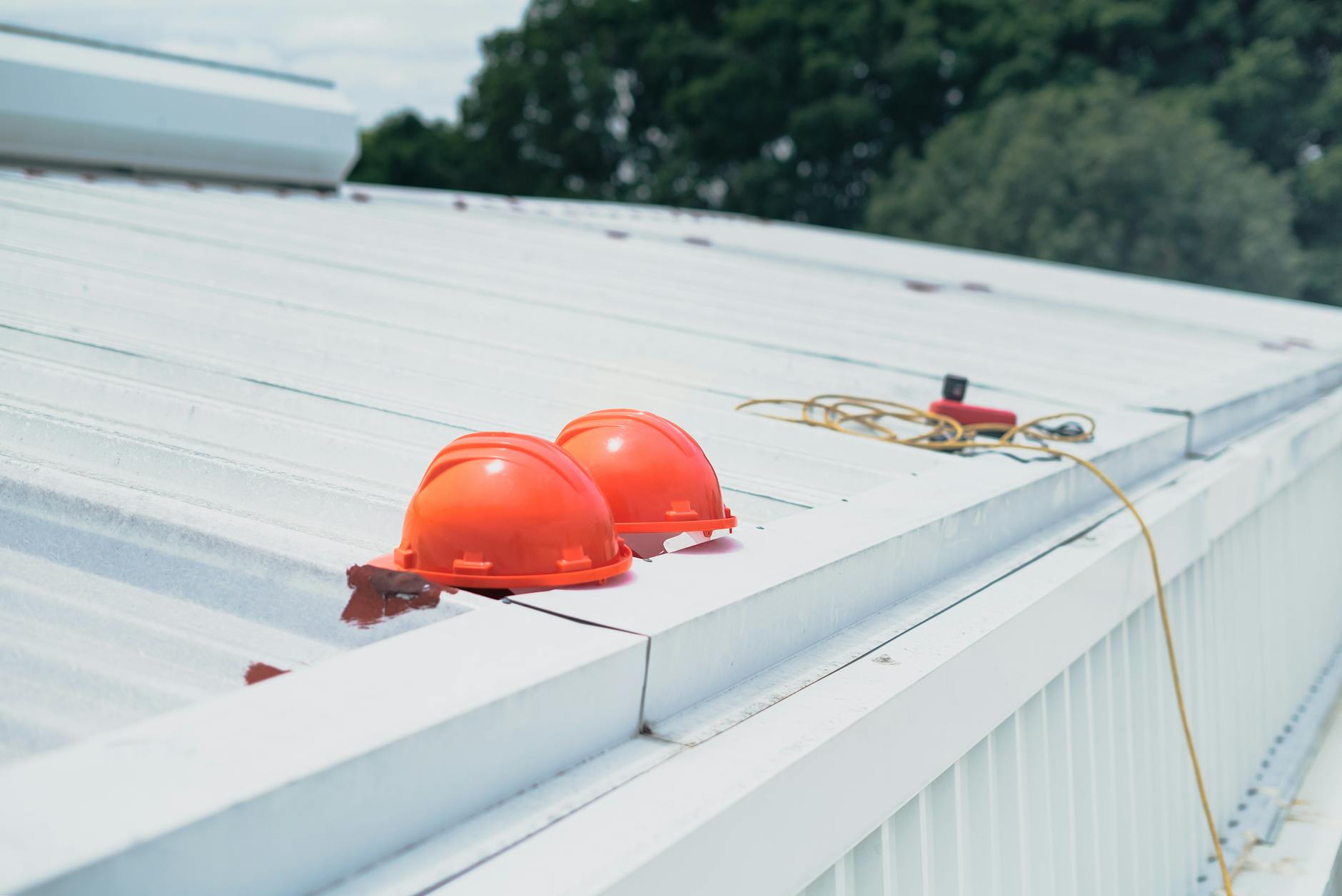 Hard hats and safety equipment resting on a metal roof during a roof inspection