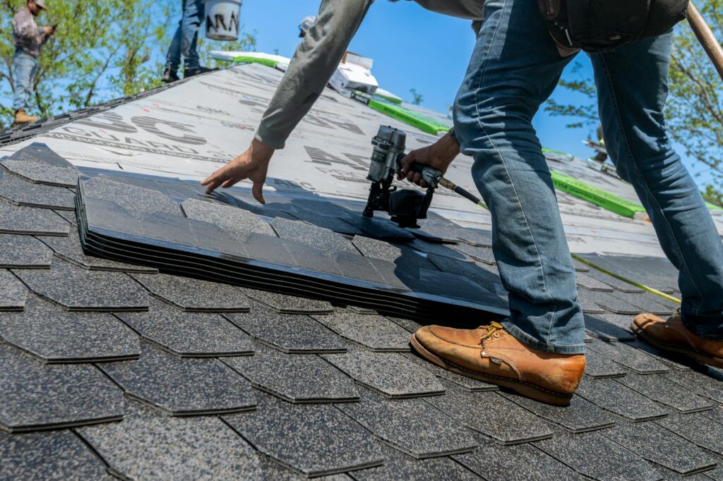 Roofer fastening new asphalt shingles on a residential roof