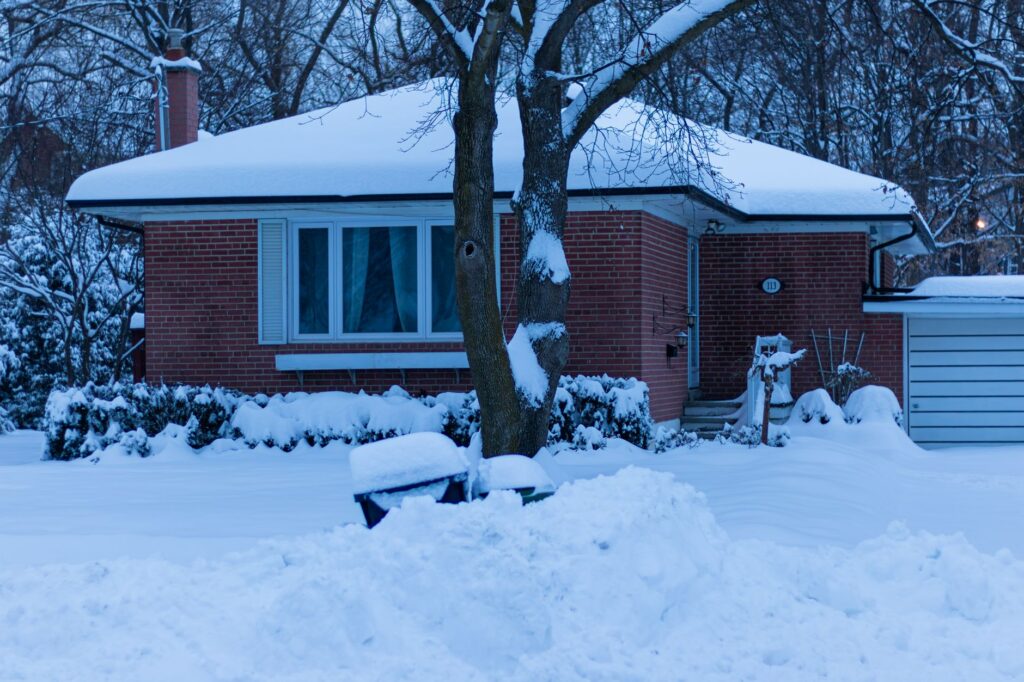 Snow piled on the roof of a two-story house during winter