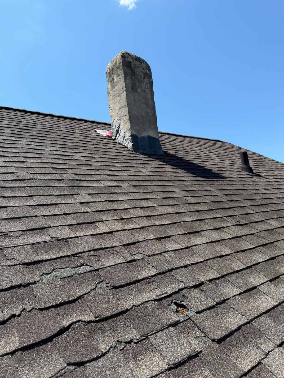 Aging asphalt shingle roof around a masonry chimney on a New Jersey home