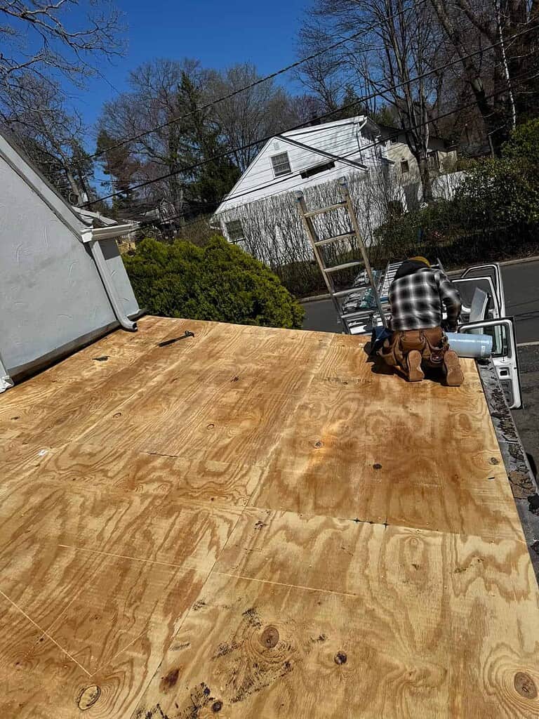 Roofer installing new plywood decking on a flat roof in New Jersey before the new membrane