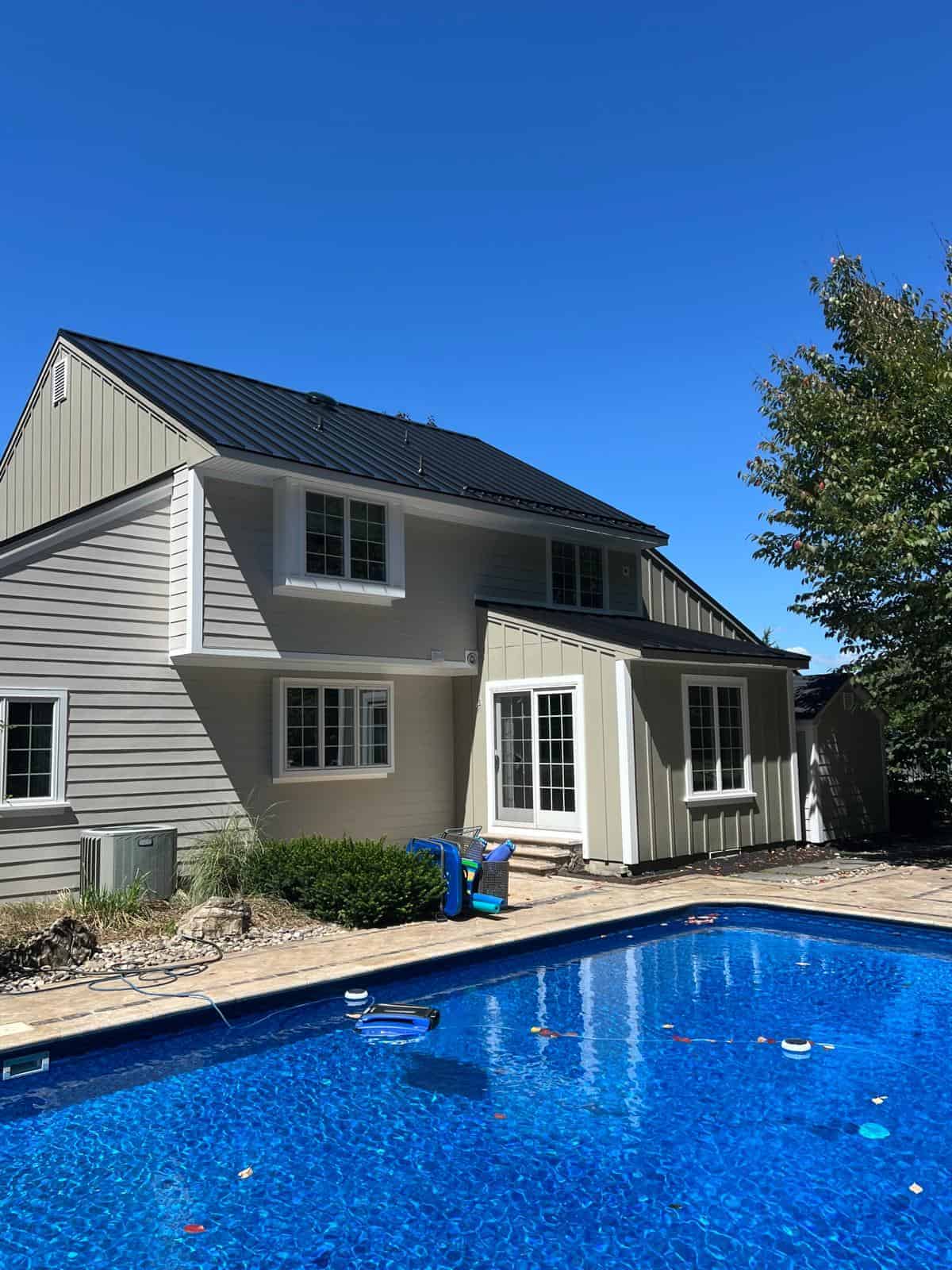 Two-story New Jersey home with gray lap siding, white trim and a dark roof, seen from the backyard pool