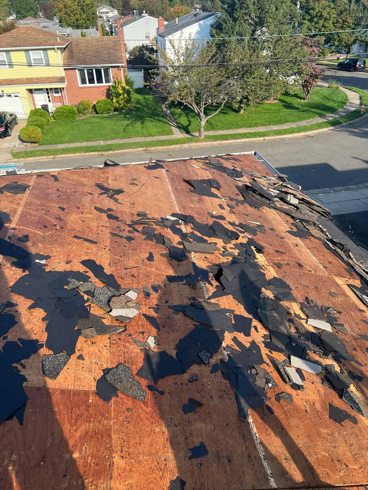 Old shingles and underlayment partly stripped from the roof deck of a New Jersey home during a tear-off
