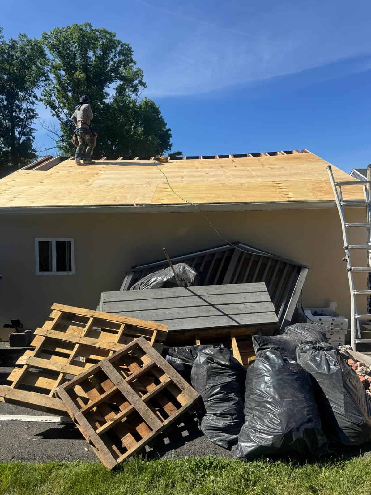 Old roofing debris bagged and stacked for removal beside a New Jersey home getting new roof decking