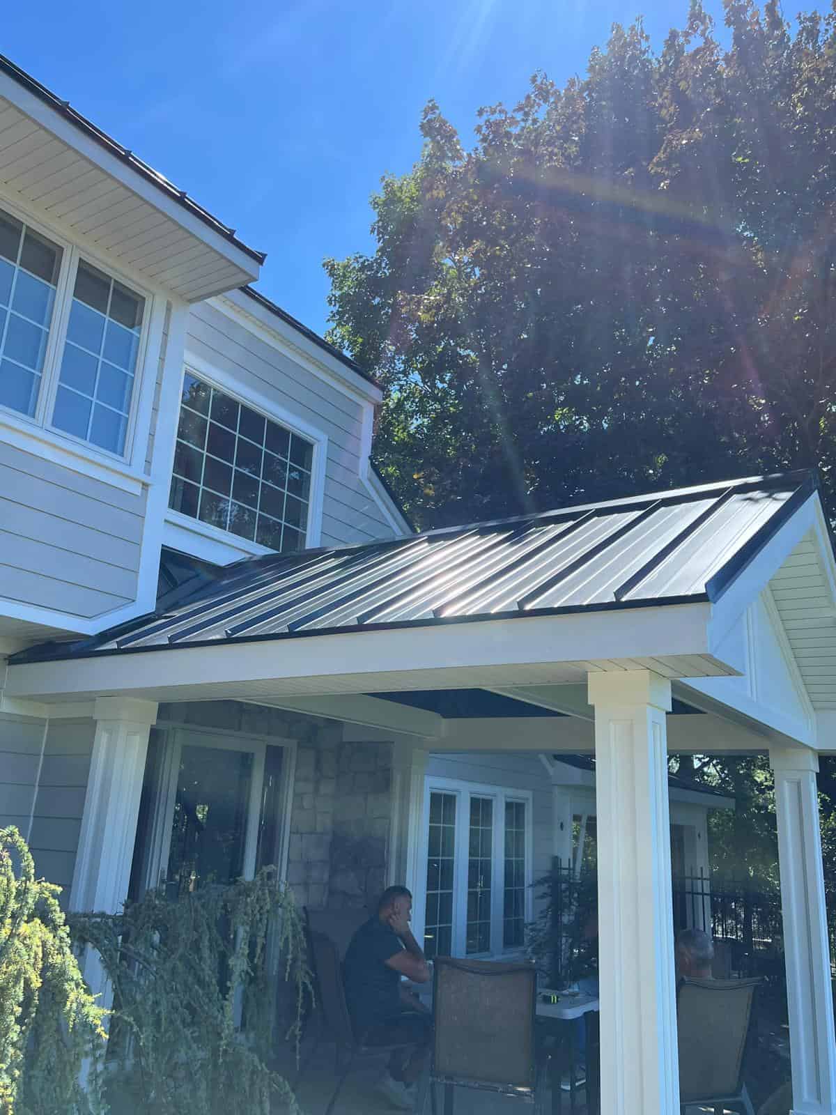 Dark standing seam metal roof over a covered back porch on a New Jersey home