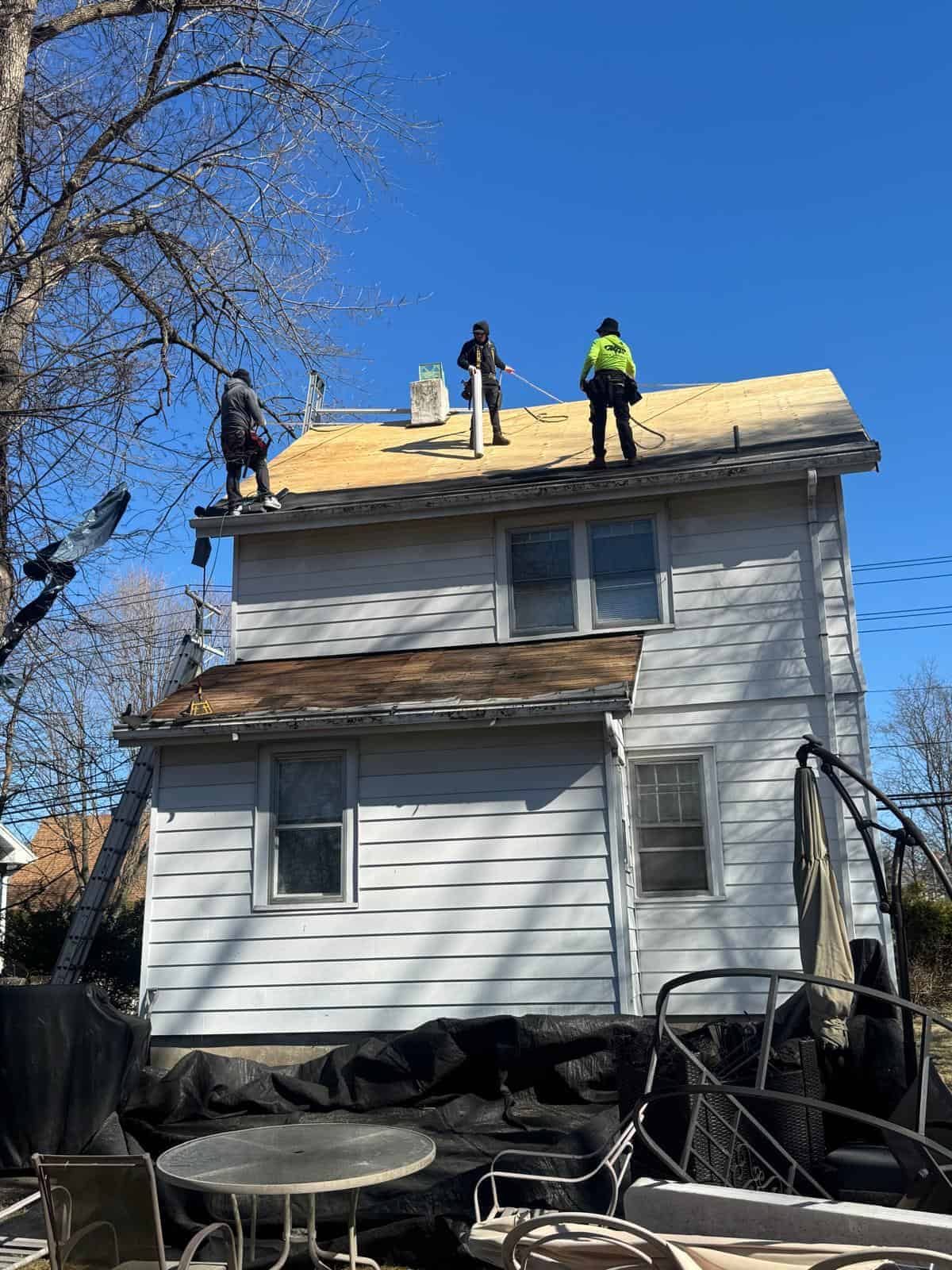 New Jersey home with white vinyl siding while Better Build Construction roofers work on the roof deck above